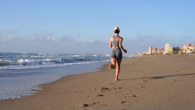 girl goes in for sports on the seashore runs along the sand along the coast