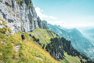 Sportive woman hikes on trail with steep slope with view on Chäeserrugg and Walensee valley....
