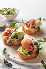 Bruschetta with ham or prosciutto, cream cheese, cucumber, spinach and microgreens. Tasty sandwich...