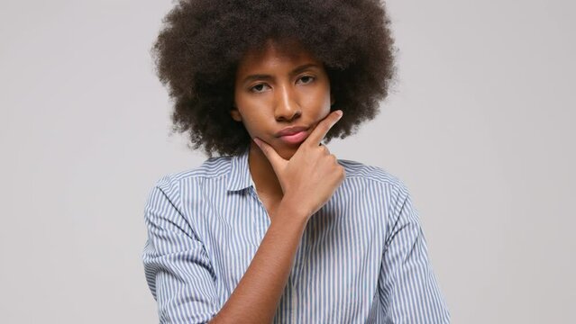Thoughtful serious afro american woman in striped shirt on grey background.