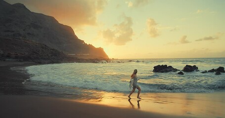 Woman walks at seaside. Slim female walking along sea water waves on beach at sunset. Travel, vacation, summer concept. Slow motion 4K	