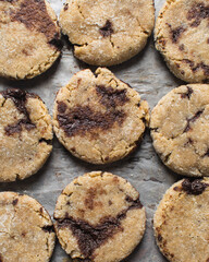 Homemade chocolate stuffed cookies on a parchment lined baking sheet, vanilla and chocolate cookies, thick vanilla cookies with a chocolate filling