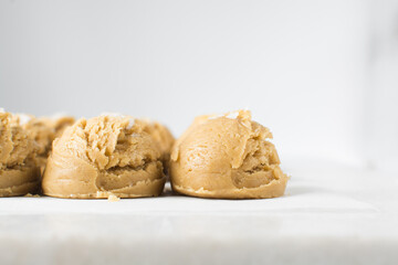 Scoops of vanilla cookie dough on a parchment lined tray, plain vanilla cookie dough with salt flakes about to be baked