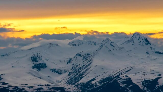 Close-up of snow-capped mountain peaks at sunset time lapse. Orange sunny sunset in the snow-capped peaks of Aragats in Armenia. Scenic mountain landscape of ice peaks