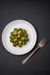 Delicious boiled Brussels sprouts on a ceramic plate on a dark concrete background
