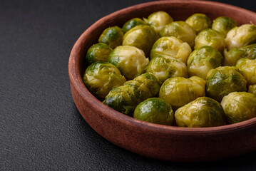 Delicious boiled Brussels sprouts on a ceramic plate on a dark concrete background