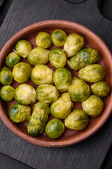 Delicious boiled Brussels sprouts on a ceramic plate on a dark concrete background