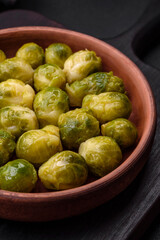 Delicious boiled Brussels sprouts on a ceramic plate on a dark concrete background