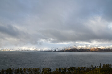 Sevan lake with a beautiful view of the snowy mountains under low clouds. One of the largest freshwater high-altitude (alpine) lakes in Eurasia. Famous natural landmark of Armenia