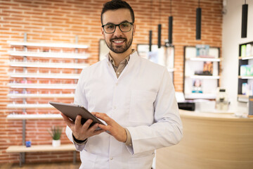 Confident specialist with tablet in optical store