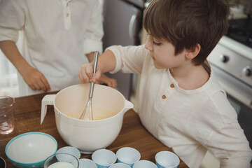 Two little boys, brothers make homemade cupcakes,  preparing dough for muffins in the kitchen....