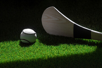 Hurling bat and sloitar on green grass. Horizontal sport theme poster, greeting cards, headers,...