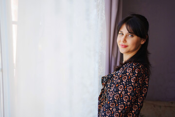 portrait of a beautiful young brunette woman in a dark dress in a home interior.