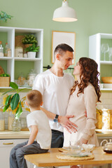 Obraz na płótnie Canvas pregnant mom, son and dad In the kitchen. a loving family. a cozy house.