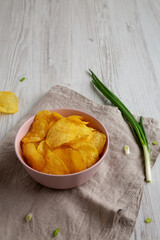 Crunch Green Onion Potato Chips in a Pink Bowl, side view. Copy space.