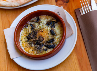 Delicious browned baked provolone cheese with champignon mushrooms served in clay bowl. Italian style cuisine