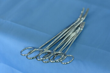 Fototapeta premium Surgical clamps and medical equipment on the surgical tray. Surgical scissors on a medical table close-up inside the operating room. Medical tools inside the operating theater on a blue table.