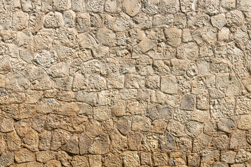 A beautiful texture of an old wall from gray and orange stones with cracks