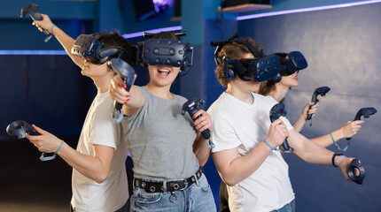 Fototapeta na wymiar group of four friends wearing virtual reality glasses and with joysticks are playing dynamic game. High quality photo