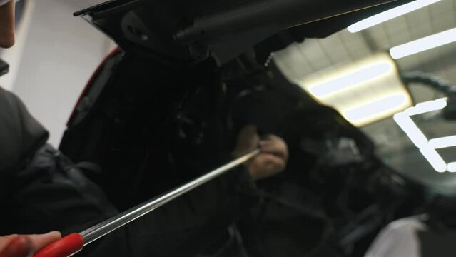 Removing a small car body dent with a dent removal rod. High quality 4k footage
