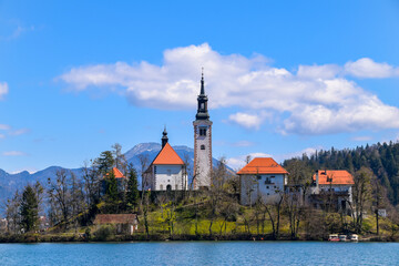 Fototapeta na wymiar Famous alpine Bled lake (Blejsko jezero) in Slovenia, amazing autumn landscape. Scenic view of the lake, island with church, Bled castle, mountains and blue sky with clouds, outdoor travel background