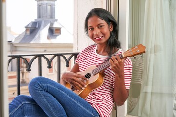 Indian woman playing ukulele on windowsill