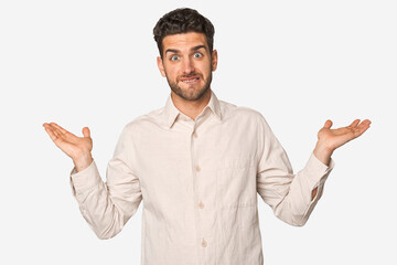 Young handsome man isolated confused and doubtful shrugging shoulders to hold a copy space.