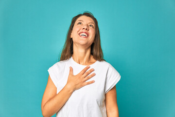 A young caucasian woman isolated laughs out loudly keeping hand on chest.