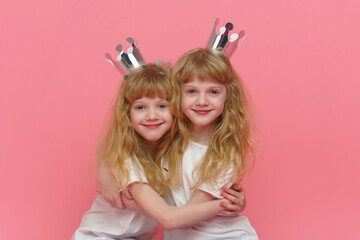 Portrait of twin girls. Two beautiful and positive curly blonde sisters who are 6 or 7 years old,...