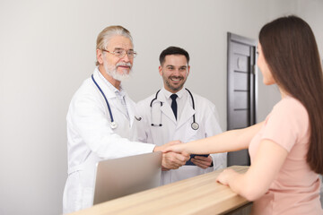 Happy senior doctor shaking hands with patient in clinic