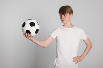 Teenage boy with soccer ball on light grey background