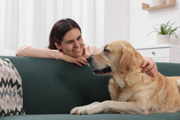 Happy woman with cute Labrador Retriever at home