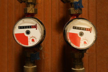 View of two electric meters near red brick wall. Water measuring device
