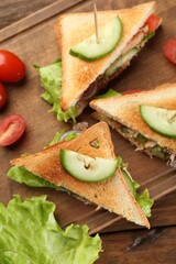 Delicious sandwiches with tuna and vegetables on wooden table, flat lay
