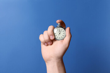 Man holding vintage timer on blue background, closeup