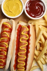 Delicious hot dogs with mustard, ketchup and potato fries on table, flat lay