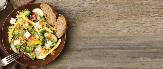 Delicious salad with lentils, cheese and vegetables served on wooden table, flat lay. Banner design with space for text