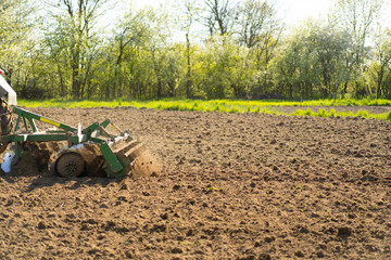 The tractor drives across the field and cultivates the land. Agricultural vehicle works in...