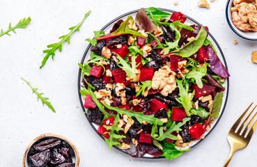 Beet and herbs healthy salad with prunes, arugula, chard and walnuts, gray table. Fresh useful vegan dish for healthy eating