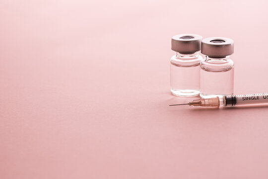 ピンクの背景にバイアル瓶と注射器　女性の美容注射や美容整形　産婦人科のイメージ写真