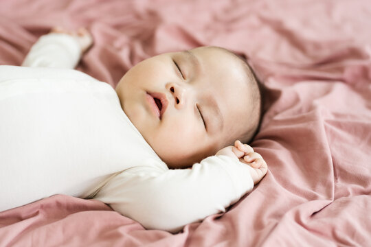 image of a newborn baby lying on a pink bed