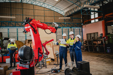 Professional engineer holding robot controller checking and repairing automatic robotic machine at...