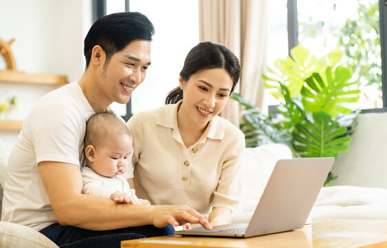image of asian family with baby sitting on sofa using laptop