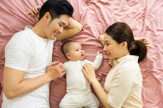 Asian family image with baby lying in bed