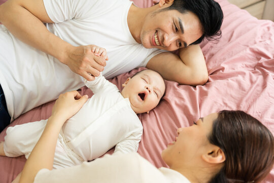 Asian family image with baby lying in bed