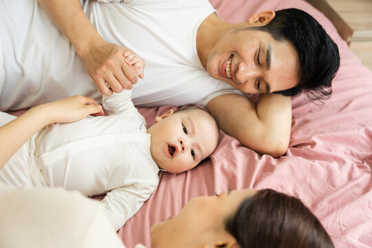 Asian family image with baby lying in bed