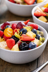 Fruit salad on a wooden table with berries and honey dressing