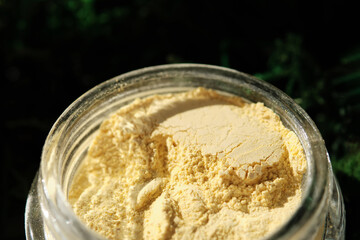 An open jar of a yellow turmeric facial scrub showing off its texture.