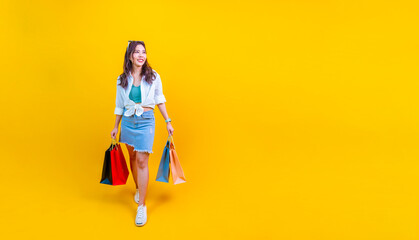Pretty Asian woman in trendy summer fashion is smiling and holding shopping bags in happiness for...