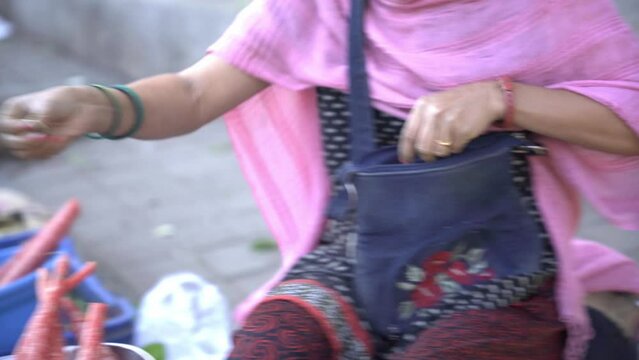 Indian vegetable street vendor counting coins while transaction and returning balance to customer